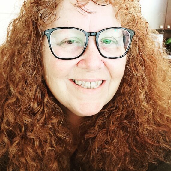 photo of a red haired woman with black rimmed glasses