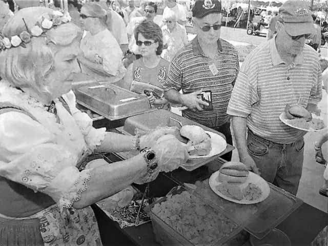 Photo of a woman in German style clothing serving food the first ever Global Market at the Arts in the Heart festival of 1982