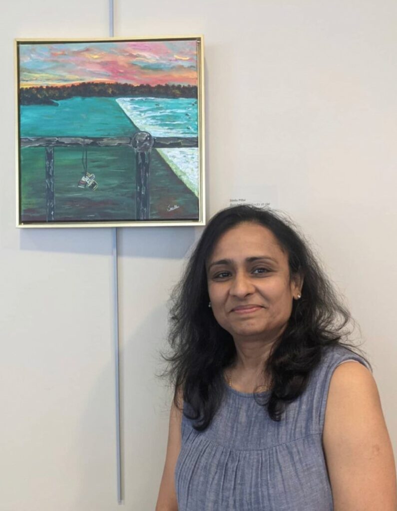 Photo of Sindhu Pillai in front of her painting