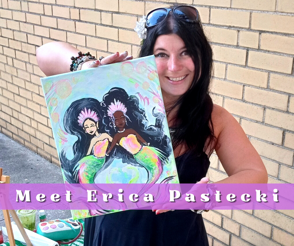photo of Erica Pastecki. She is sitting infront of a brick wall holding a painting she finished of two mermaids. She is wearing a black dress and dark sunglasses. She has pale skin with freckles, and jet black hair. She is smiling.