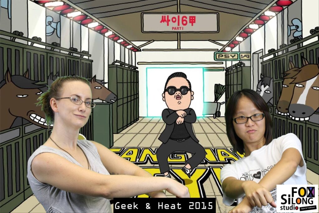 Two women doing the gangnam style dance in front of a green screen that is projecting a cartoon gangnam character.