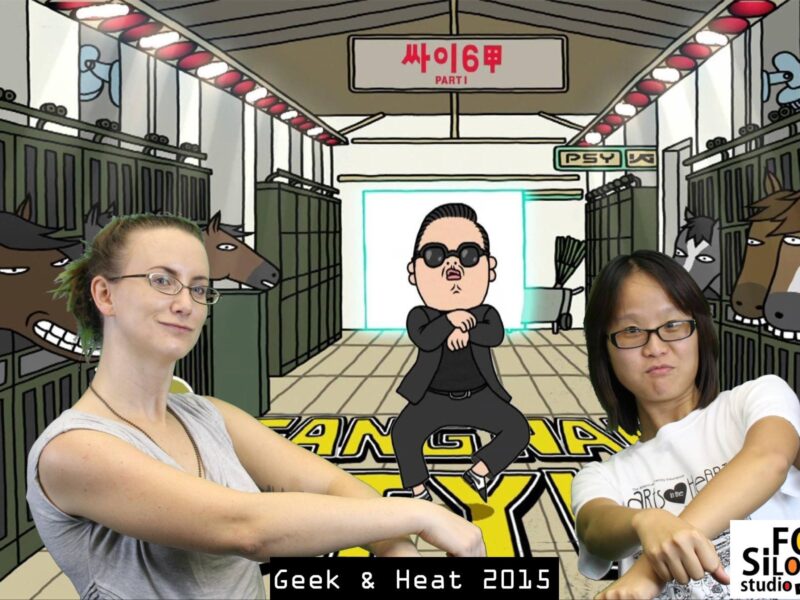 Christina Berkshire (Left) is a Caucasian woman wearing a light grey tank top and glasses. She has brown hair that is up in a pony tail. Fox Si-Long Chen (right) is of Taiwanese descent, is wearing a white tshirt and black framed glasses. She has short dark hair parted down the middle. Both women are standing in front of a green screen with gangnam style cartoon playing on it. Both girls are dancing with the character.
