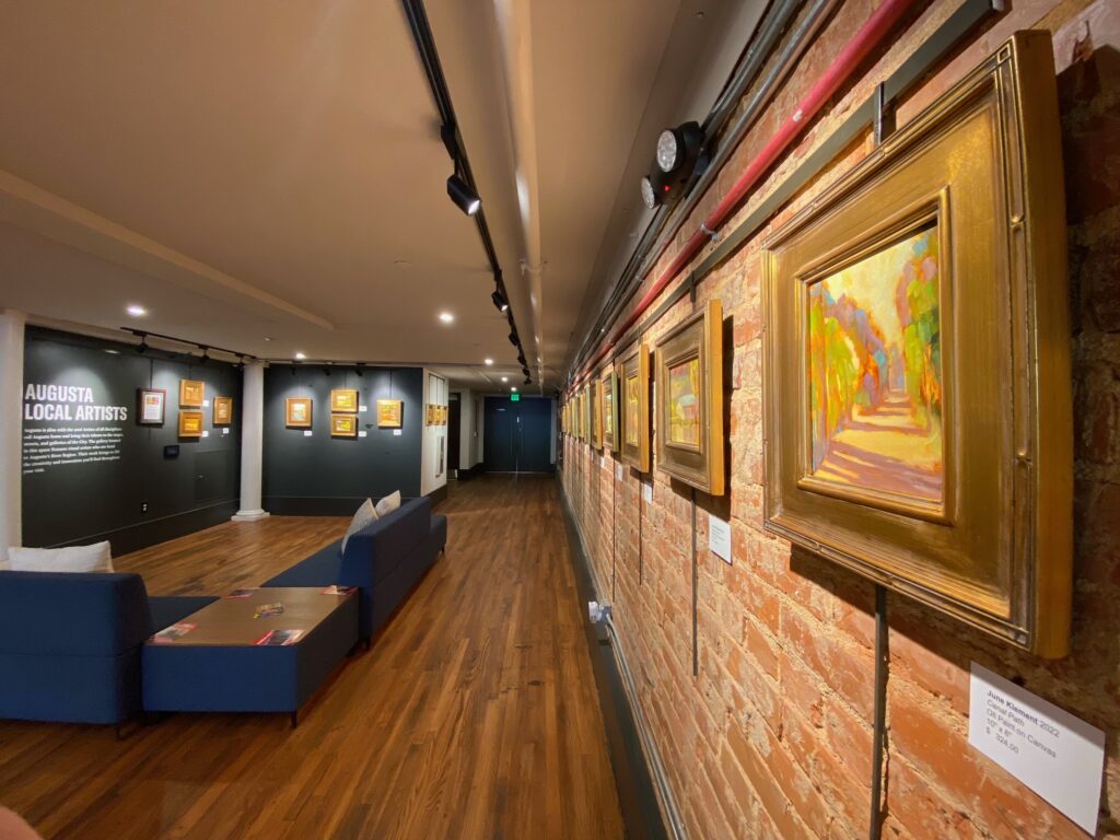 Photo of the inside of the Augusta & Co. Gallery featuring June Klements solo exhibition of oil paintings that portray landscapes and waterways from around Augusta, GA.