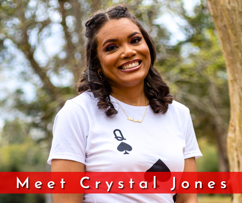 Crystal Jones is a woman with brown curly hair. She is waring a queen of spades tshirt and smiling.