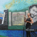 Nefertiti Robinson singing in front of Golden Blocks mural