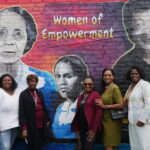 Group photo including women from the Walker family in front of the mural