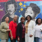 Group photo including Monique Walker in front of the mural