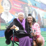 Salonika Rhyne and Ruth B. Crawford smiling in front of the mural