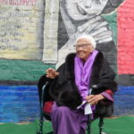 Ruth B. Crawford in front of her portrait on the mural