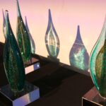 Photo of Arts Awards. They are tear-drop shaped with blue and green glitter gass on a brass stand.