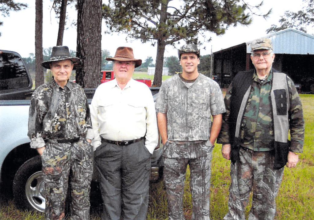 Charles Bowen and 3 of his male friends standing in hunting camo