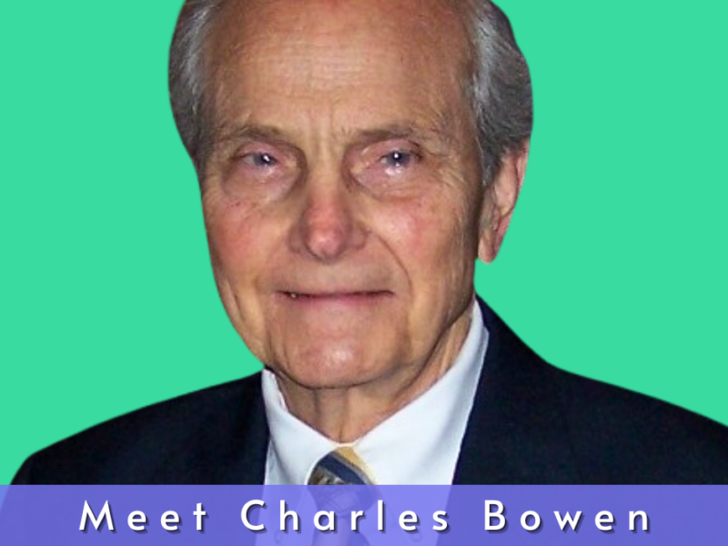 Photo of Charles Bowen. He is a Caucasian man with white hair and blue eyes. He is wearing a black suit and tie.