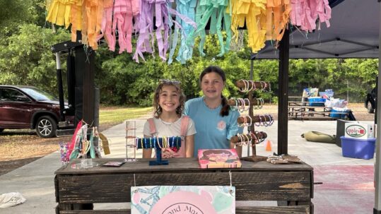 Maycie Moore and Emma Statkus selling bracelets at their booth