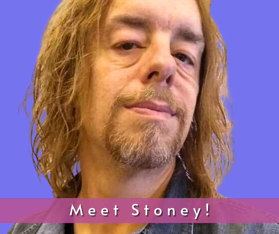 John "Stoney" Cannon is a Caucasian male with sandy brown hair to his shoulders. He has brown eyes and is wearing a denim button down shirt.