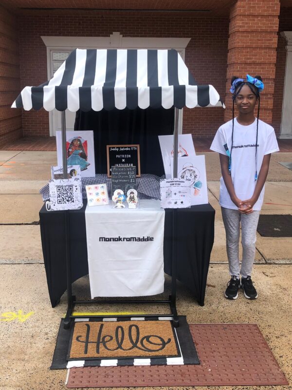 Young African American Girl selling her art at her booth at Arts in the Heart of Augusta's Young Artist Market