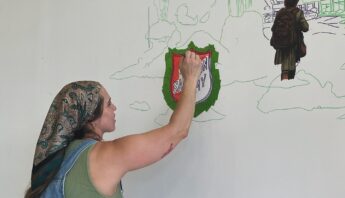 Photo of woman painting a mural.