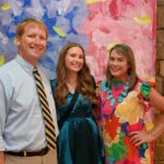 A Caucasian family smiling in front of a pink and blue backdrop.