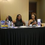 Three African American women at a check-in table for an event