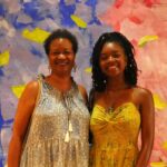 A African American mother and daughter posing for a photo in front of a painted backdrop