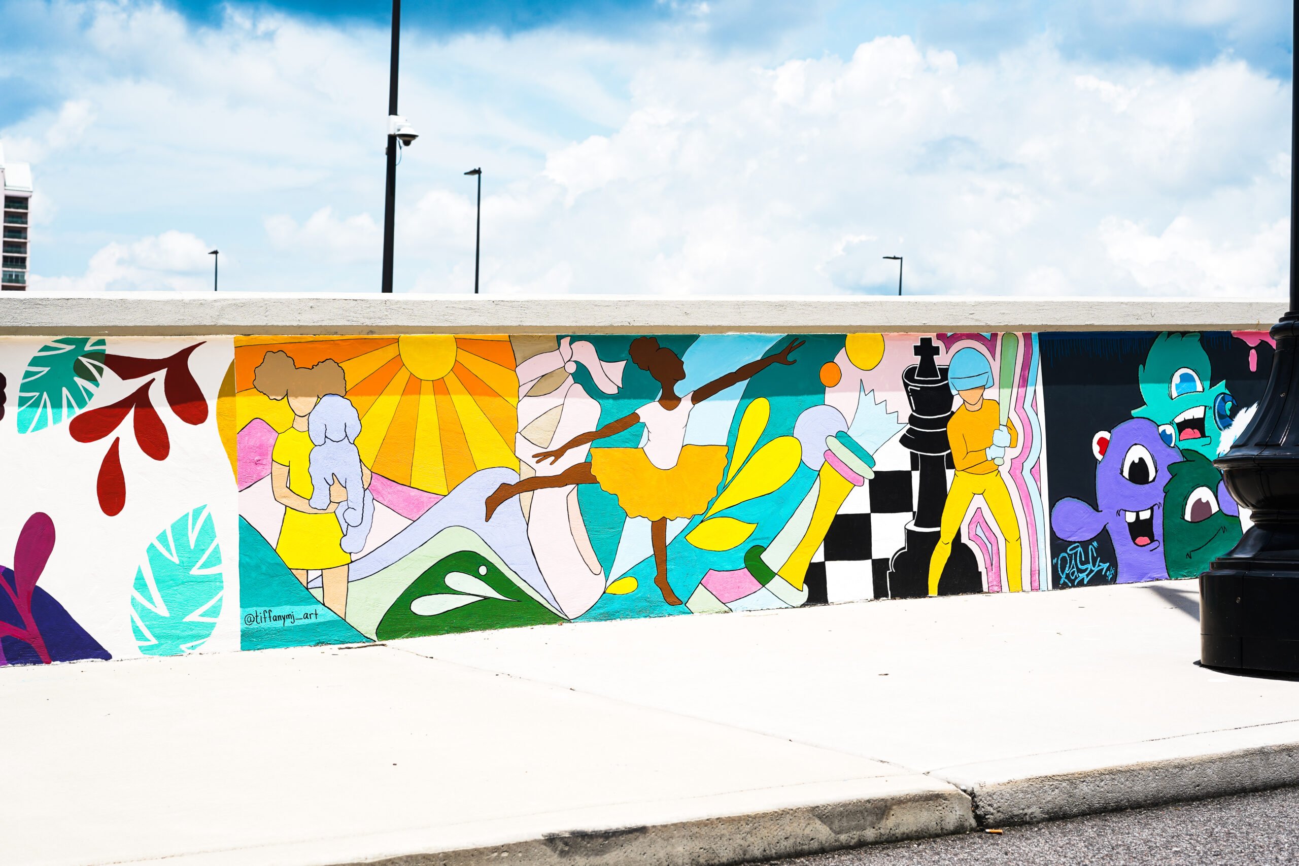 Photo of a colorful mural on the wall of a bridge. It features a young girl dancing ballet.