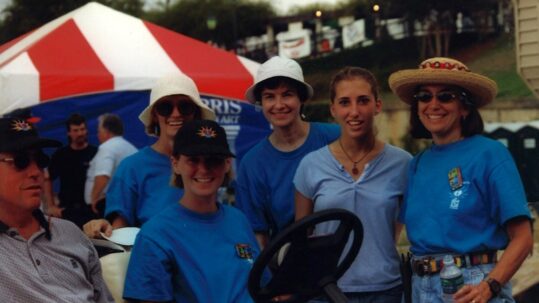 A group of volunteers in blue shirts stand for a photo.