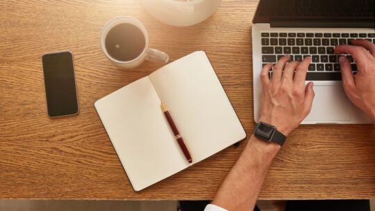 An author working on his laptop. He is drinking a coffee.