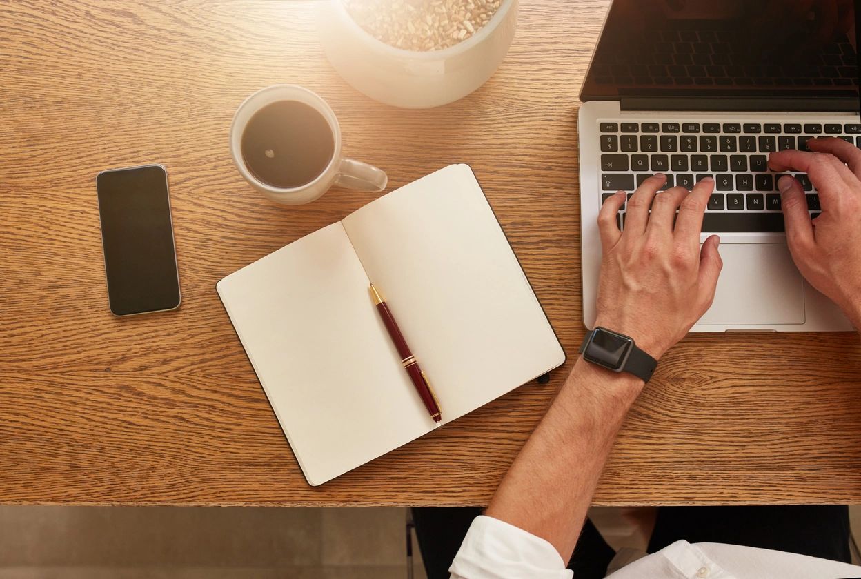 An author working on his laptop. He is drinking a coffee.