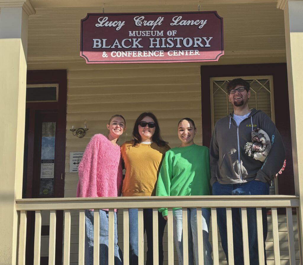 4 people standing under the Lucy Craft Laney Museum of Black History sign.